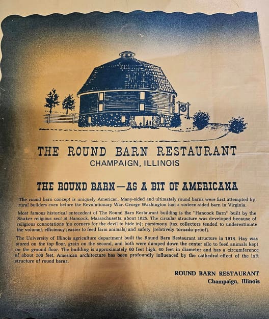 A vintage blue promotional card illustrating the round barn restaurant above a printed history of the building.